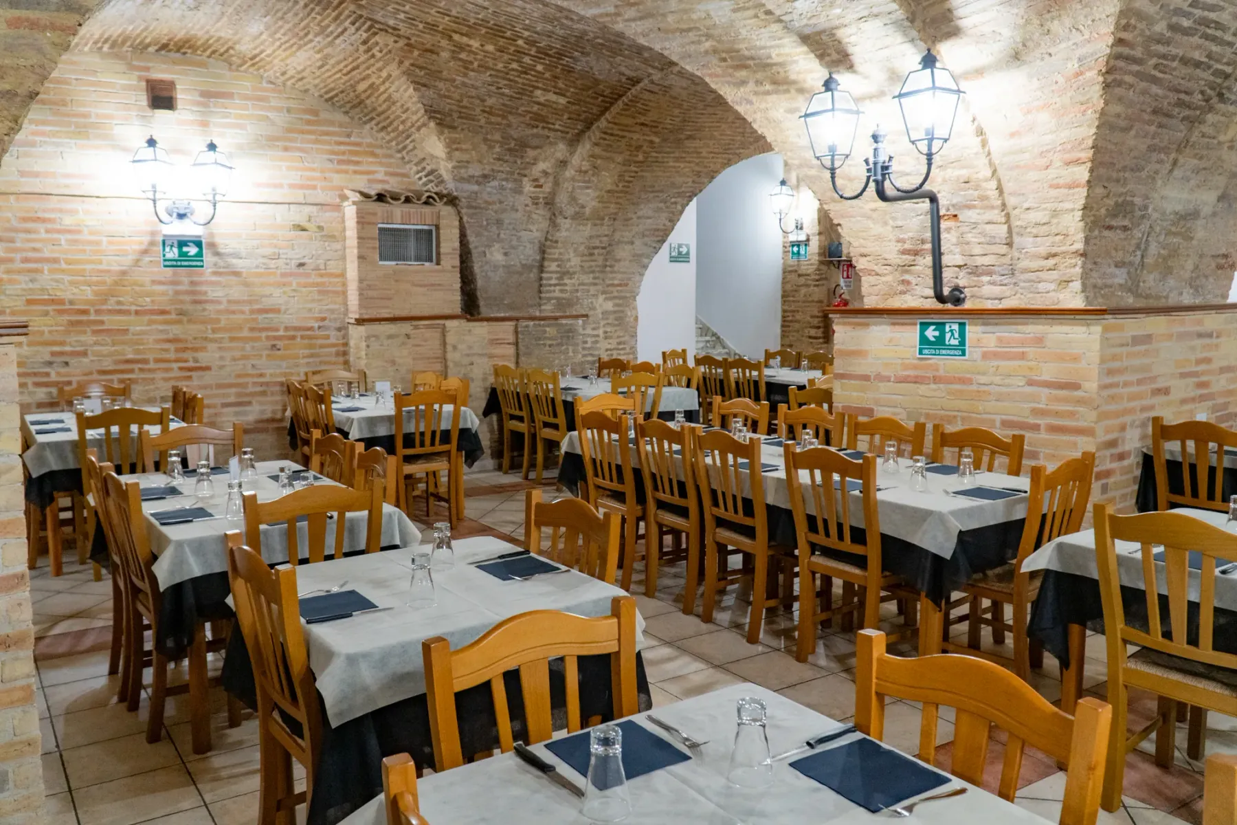 La sala calda e accogliente di Pizzeria 5 Archi con le caratteristiche arcate in mattoni a vista e i tavoli apparecchiati